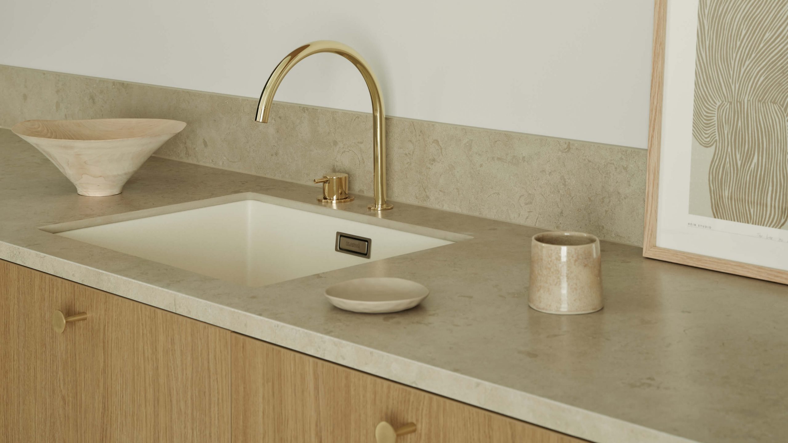 Ljus bänkskiva i kalksten tillsammans med ekluckor och knoppar i guld