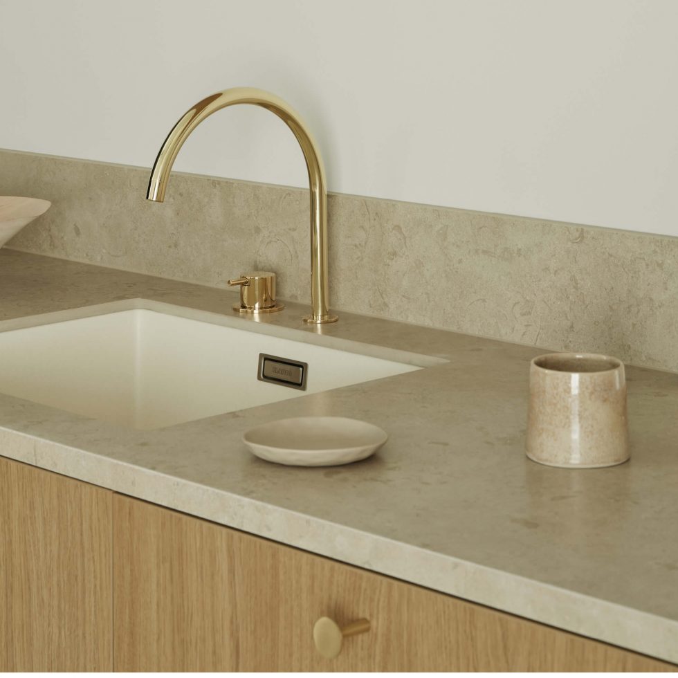 Ljus bänkskiva i kalksten tillsammans med ekluckor och knoppar i guld