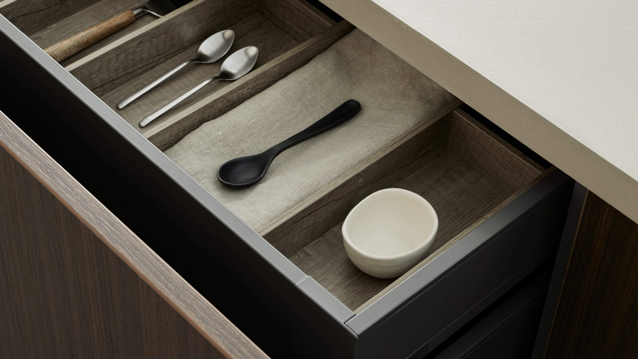 Lådinredning i mörkt grå färg med avdelare i trä