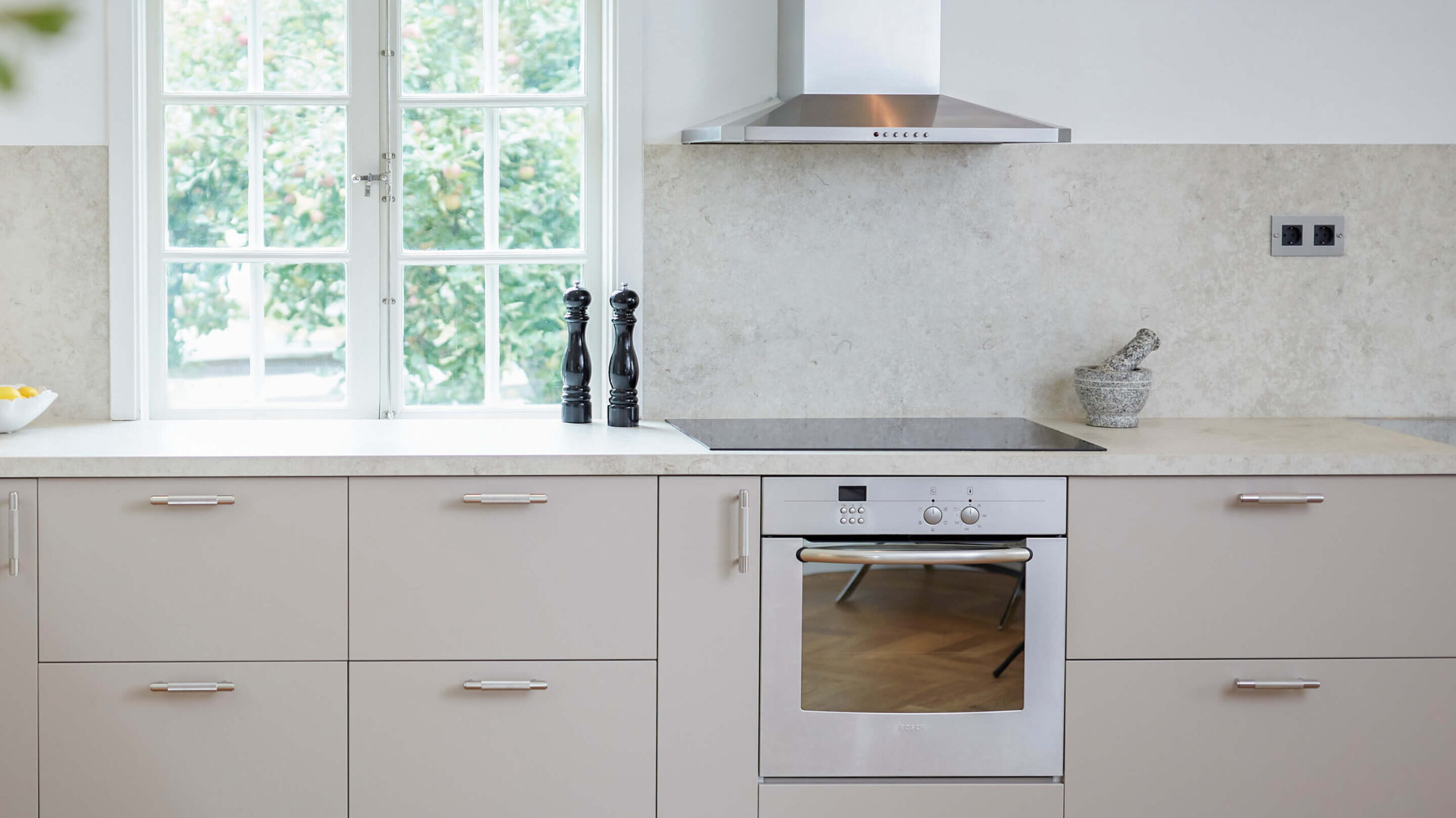 Ljus, grå kökslucka tillsammans med en stenmönstrad bänkskiva